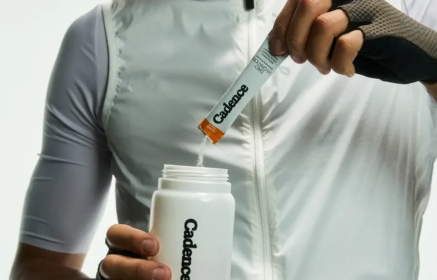 A cyclist tipping a Cadence sachet into a bottle