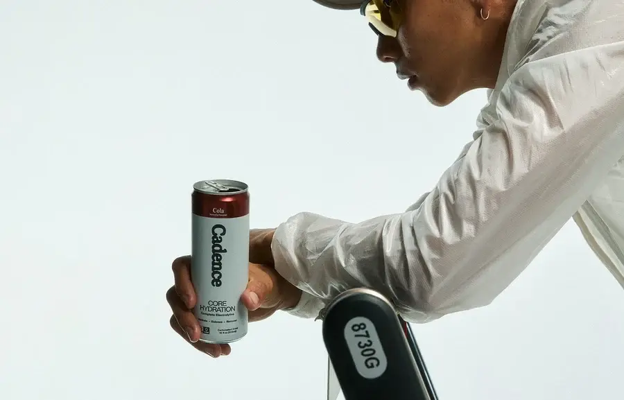 A cyclist holding a Cadence can beside a turbo trainer