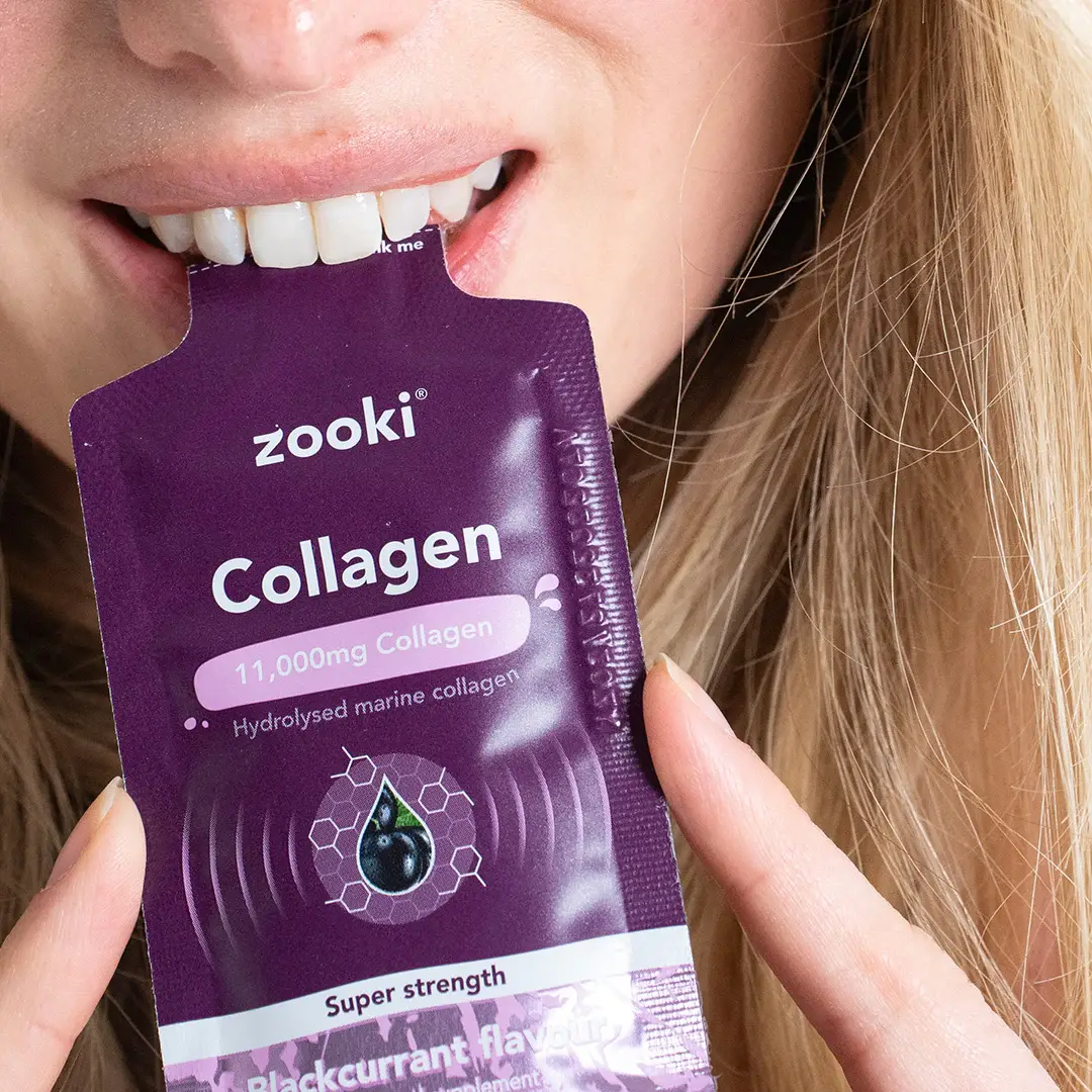 A woman holding a purple Zooki Collagen sachet