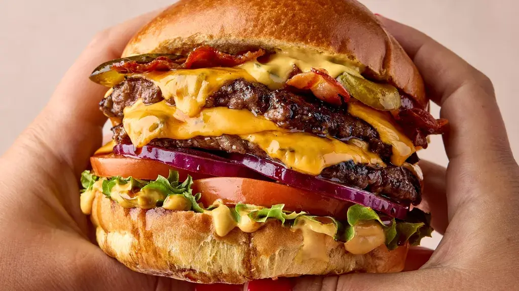 A double cheeseburger held in both hands
